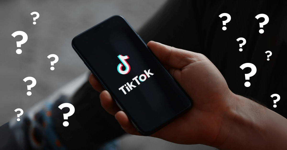 A hand holding a phone, which displays TikTok app, surrounded by question marks.